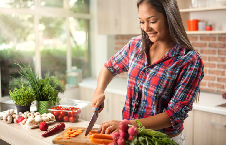 young asian woman chopping vegetables for detox in kitchen